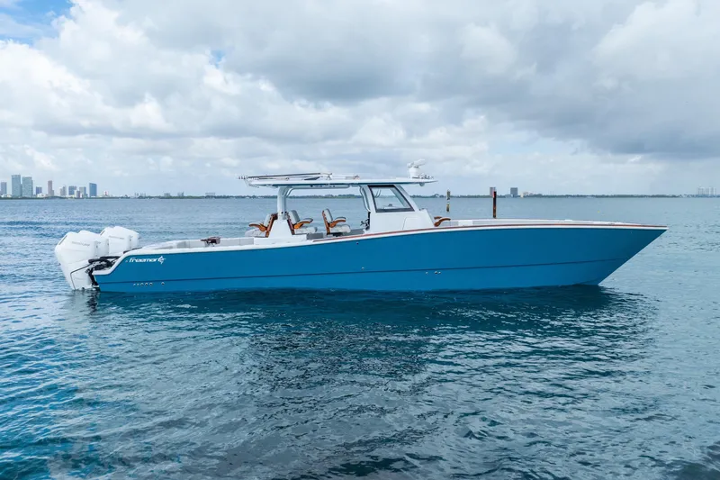Slide: The Image of 2024 Freeman 47 boat on calm water with city skyline in background. - 12