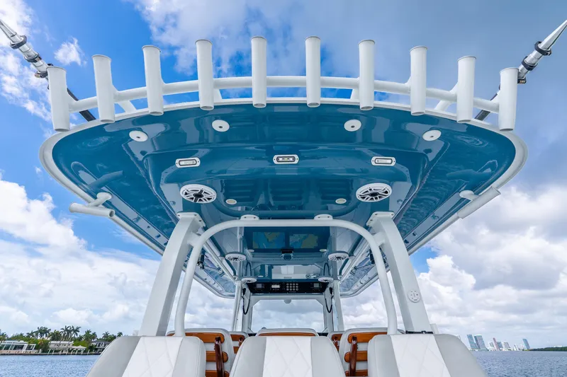 Slide: The Image of 2024 Freeman 47 boat with sleek blue canopy and rod holders against a cloudy sky. - 50