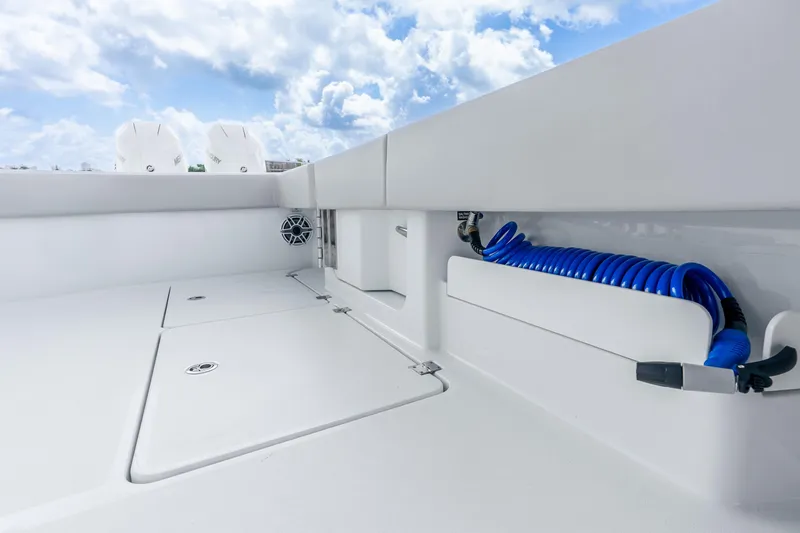 Slide: The Image of 2024 Freeman 47 boat deck with storage compartments and coiled blue hose. - 56