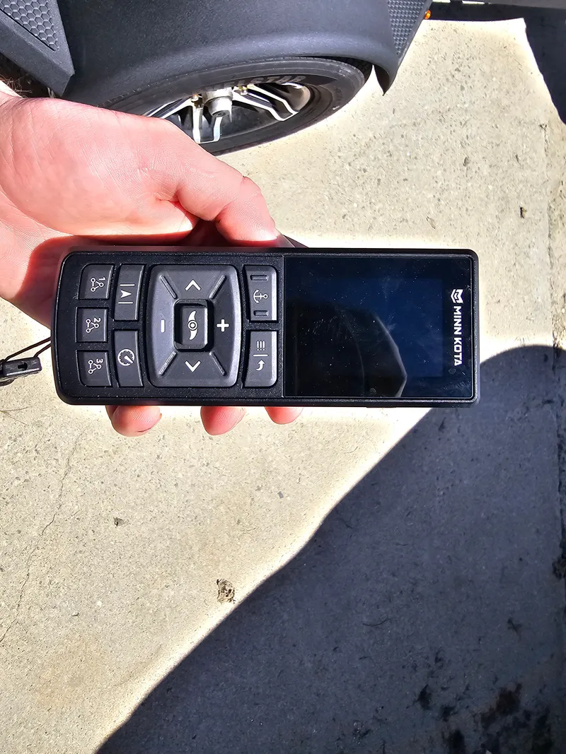 Slide: The Image of Hand holding Minn Kota remote beside Tracker Proteam 175, 2025. - 12