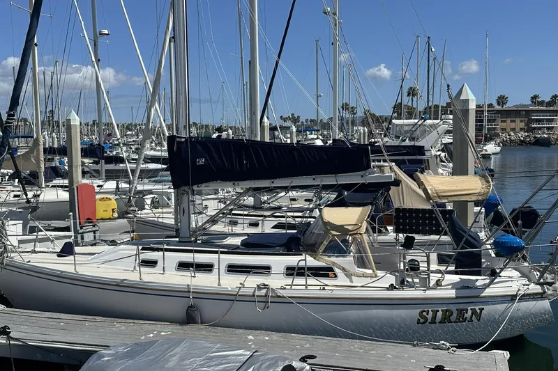Slide: The Image of 1989 Catalina 36 MkII sailboat named "Siren" docked in a marina under clear skies. - 10