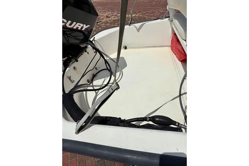 Slide: The Image of 2002 Boston Whaler 130 Sport boat interior with Mercury engine and red storage box. - 13