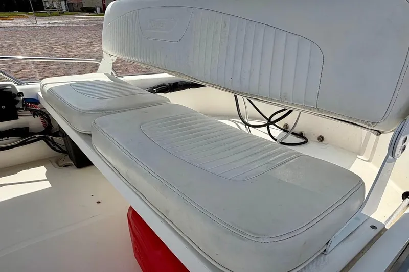 Slide: The Image of 2002 Boston Whaler 130 Sport boat interior with white cushioned seating. - 14