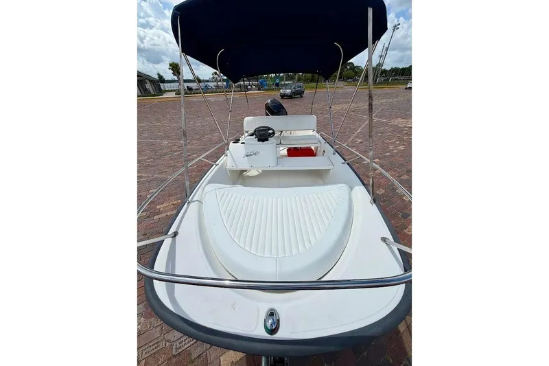 Slide: The Image of 2002 Boston Whaler 130 Sport boat with canopy, parked on brick pavement. - 6