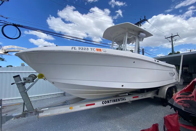 The Image of 2022 Robalo R242 Center Console boat on trailer under blue sky. - 0