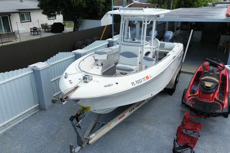 Slide: The Image of 2022 Robalo R242 Center Console boat on trailer, parked beside a red jet ski. - 11
