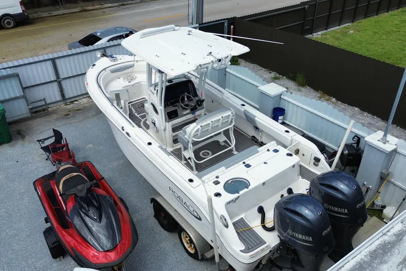 Slide: The Image of 2022 Robalo R242 Center Console boat with Yamaha engines, parked beside a red jet ski. - 16