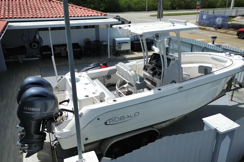 Slide: The Image of 2022 Robalo R242 Center Console boat with Yamaha engines, parked in a fenced area. - 18