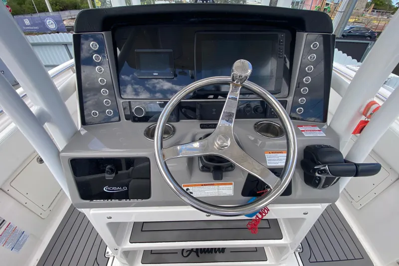 Slide: The Image of 2022 Robalo R242 Center Console boat dashboard with steering wheel and controls. - 28
