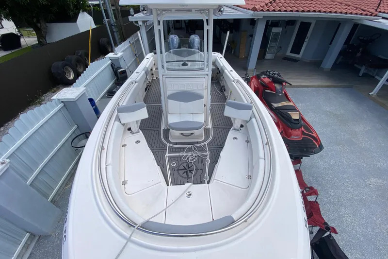Slide: The Image of 2022 Robalo R242 Center Console boat docked, featuring spacious deck and seating. - 37