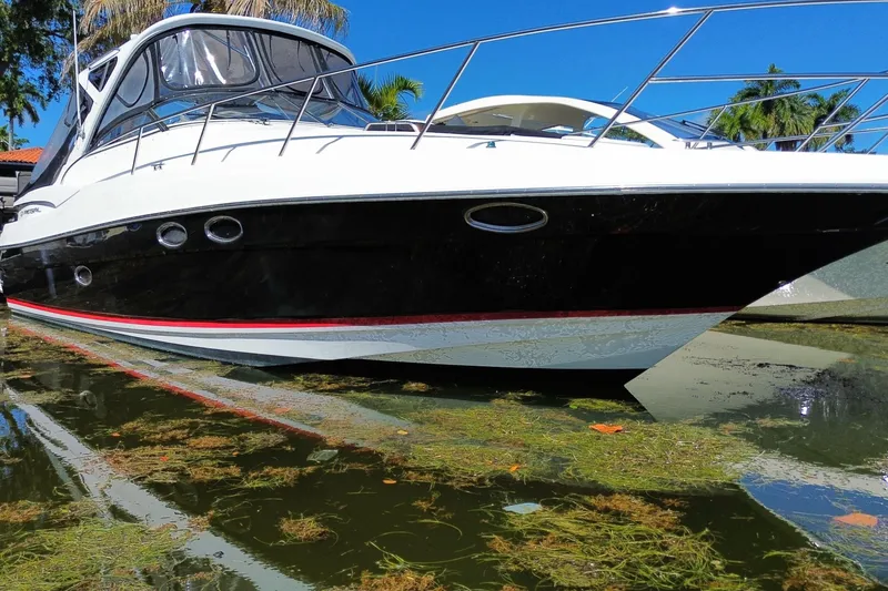 Slide: The Image of 2006 Regal Commodore 3560 IB yacht docked in clear water, surrounded by greenery. - 2