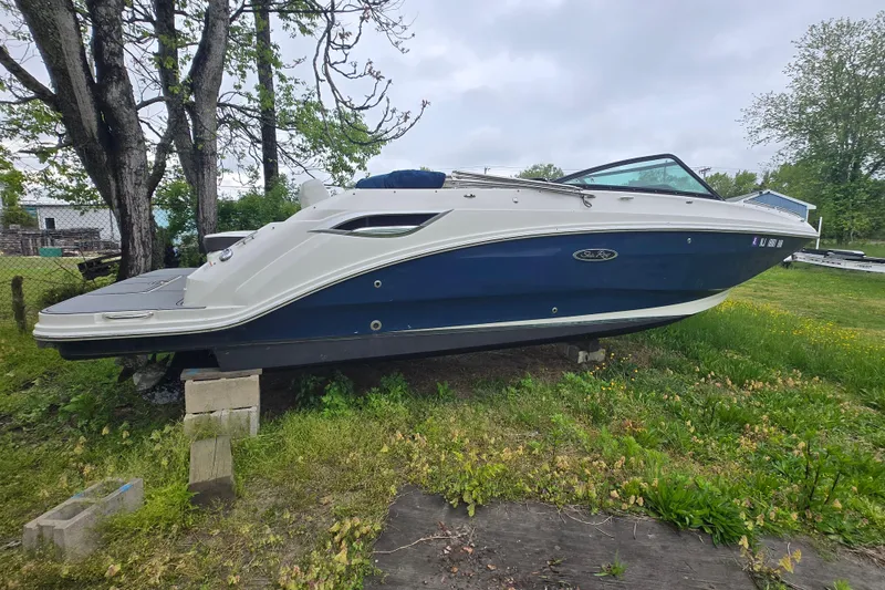 Slide: The Image of 2018 Sea Ray SDX 250 boat on blocks, parked on grassy area near trees. - 16