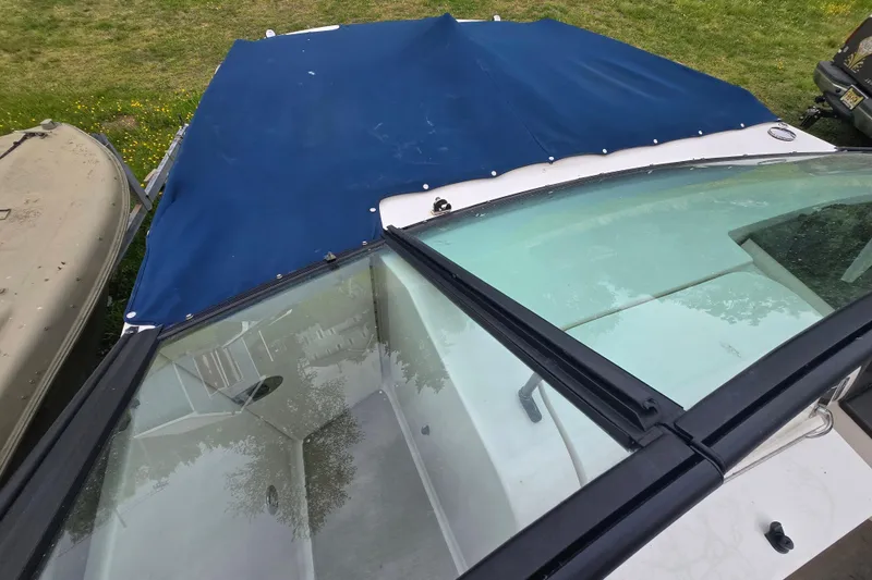 Slide: The Image of 2018 Sea Ray SDX 250 boat with blue cover, parked on grass. - 24