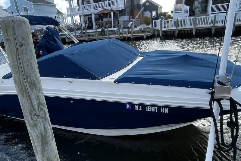 Slide: The Image of 2018 Sea Ray SDX 250 boat docked with blue cover, residential waterfront background. - 3