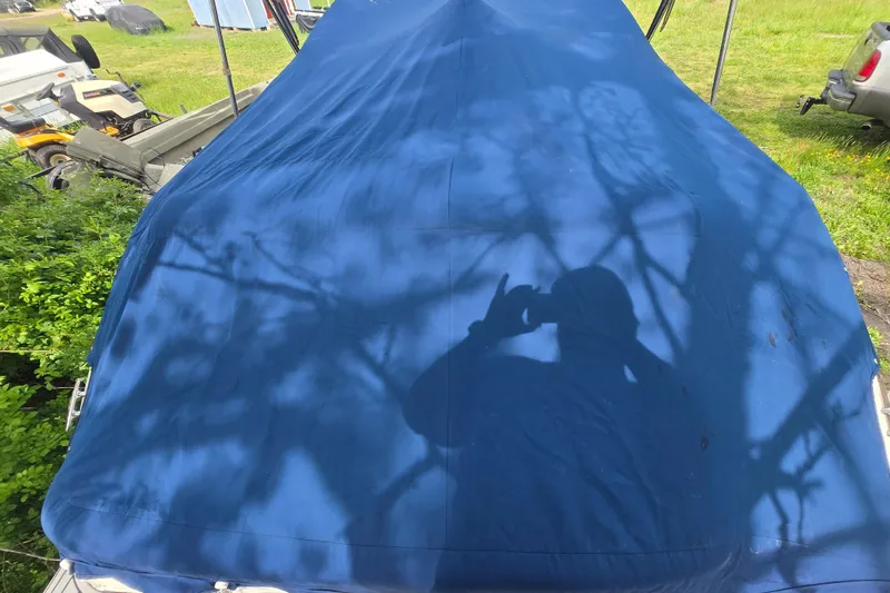 Slide: The Image of Covered 2018 Sea Ray SDX 250 boat with blue tarp, shadowed by trees. - 35