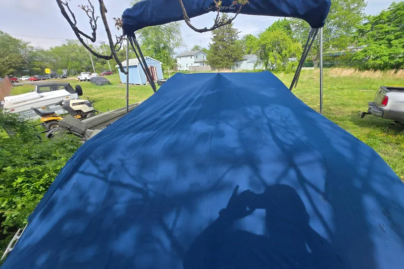 Slide: The Image of 2018 Sea Ray SDX 250 boat with blue cover in a grassy yard. - 36
