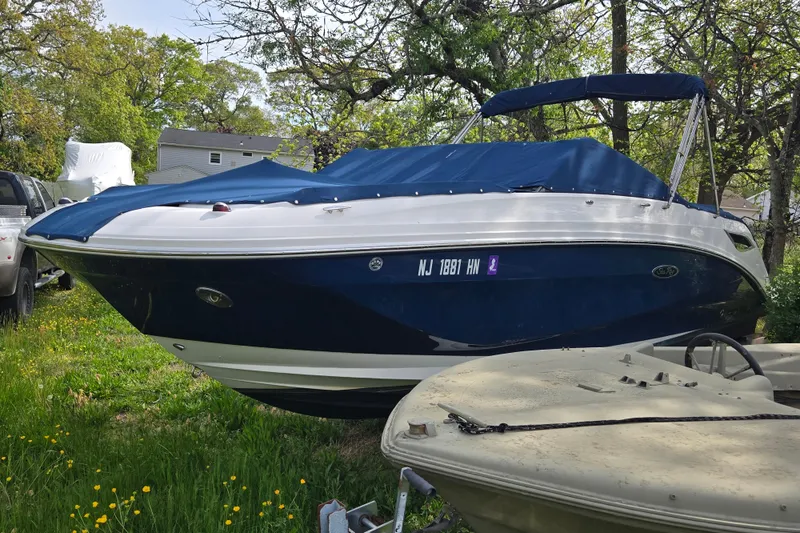 Slide: The Image of 2018 Sea Ray SDX 250 boat with blue cover, parked on grass. - 37