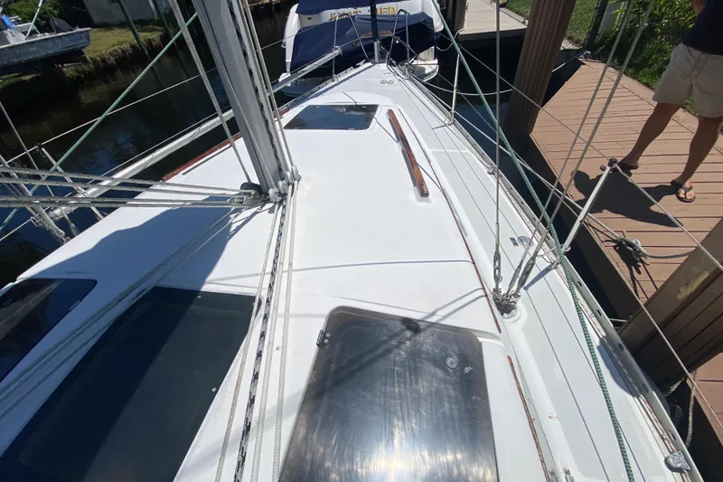 Slide: The Image of 1995 Hunter 33.5 sailboat deck view, docked with visible rigging and wooden accents. - 10