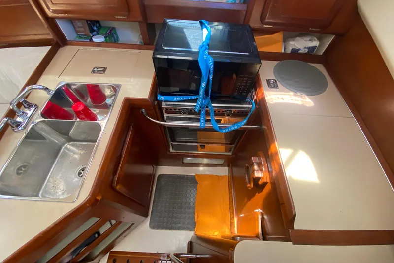 Slide: The Image of Interior of 1995 Hunter 33.5 sailboat kitchen with stove, sink, and storage cabinets. - 23