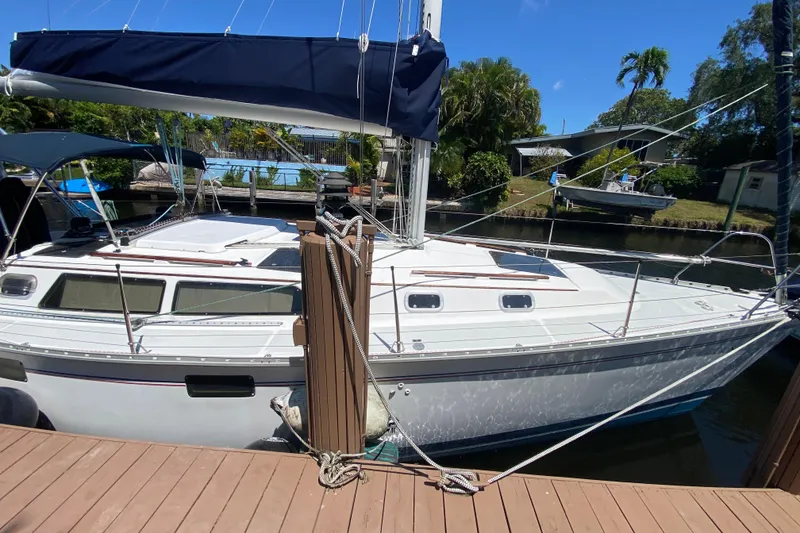 Slide: The Image of 1995 Hunter 33.5 sailboat docked, featuring sleek design and blue sail cover. - 3