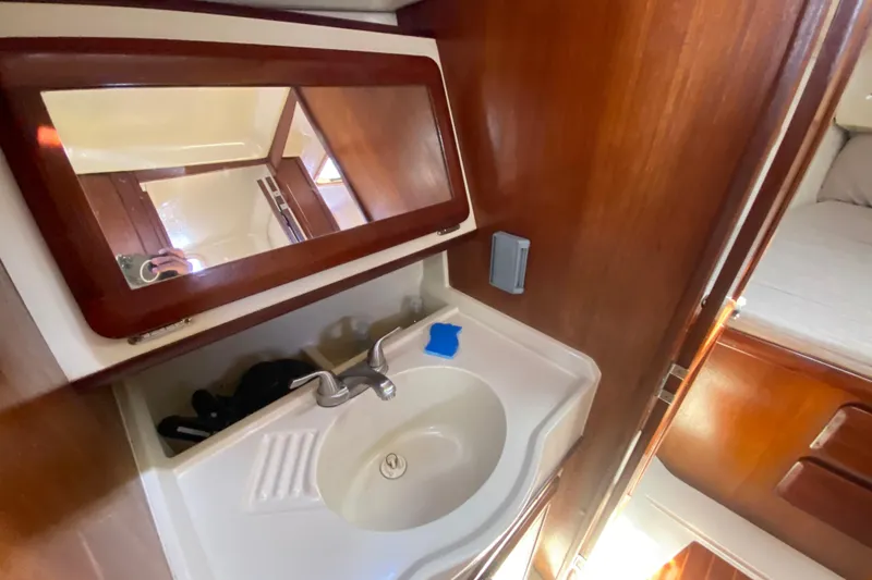 Slide: The Image of 1995 Hunter 33.5 yacht bathroom with sink, mirror, and wooden cabinetry. - 34