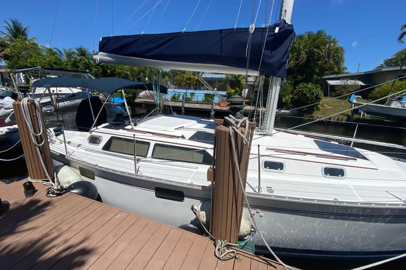 Slide: The Image of 1995 Hunter 33.5 sailboat docked, featuring a sleek design and blue canopy. - 4