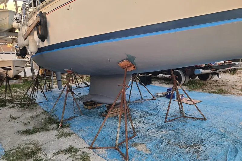 Slide: The Image of 1995 Hunter 33.5 sailboat on stands, undergoing maintenance on a blue tarp. - 57