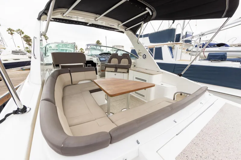 Slide: The Image of 2015 Sea Ray Sundancer 350 yacht with spacious seating and table, docked at marina. - 9