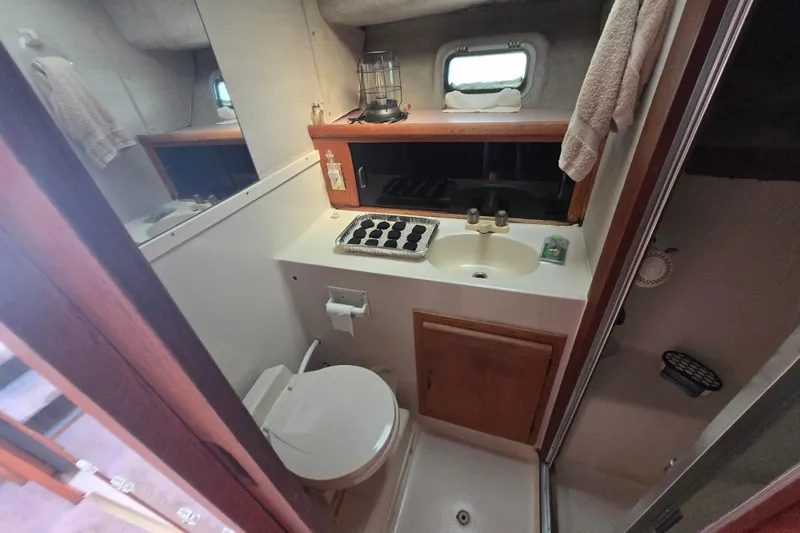Slide: The Image of 1988 Silverton 34 Convertible boat bathroom with sink, toilet, and window. - 16
