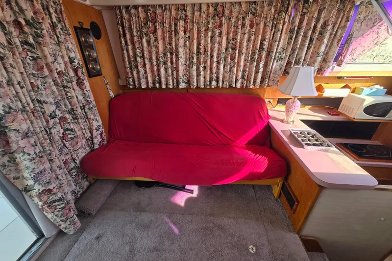 Slide: The Image of Interior of 1988 Silverton 34 Convertible with red sofa, floral curtains, and kitchenette. - 6