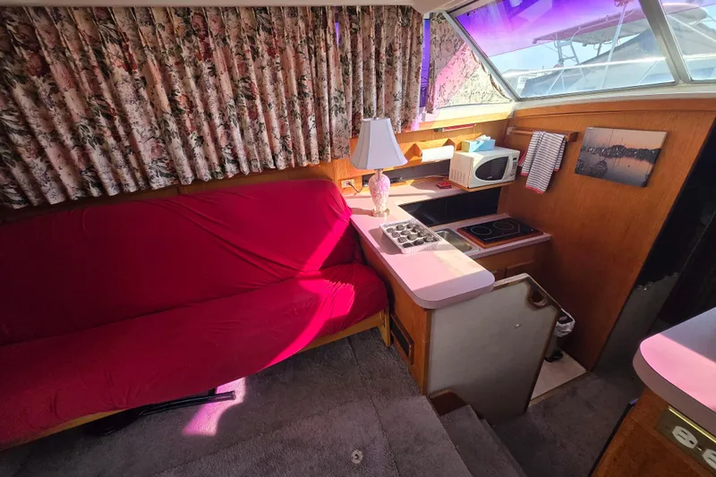 Slide: The Image of Interior of 1988 Silverton 34 Convertible with red sofa, kitchenette, and floral curtains. - 7