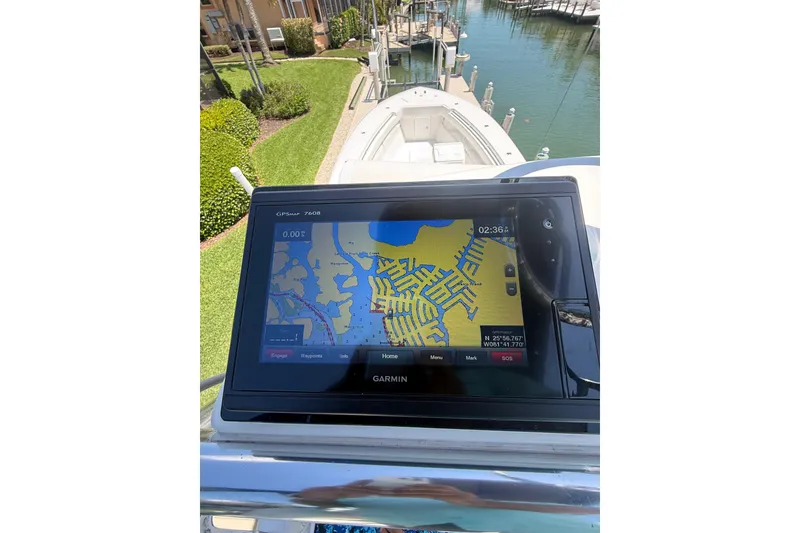 Slide: The Image of Garmin GPS on 2012 Invincible 42 Open Fisherman boat, docked near lush greenery. - 38