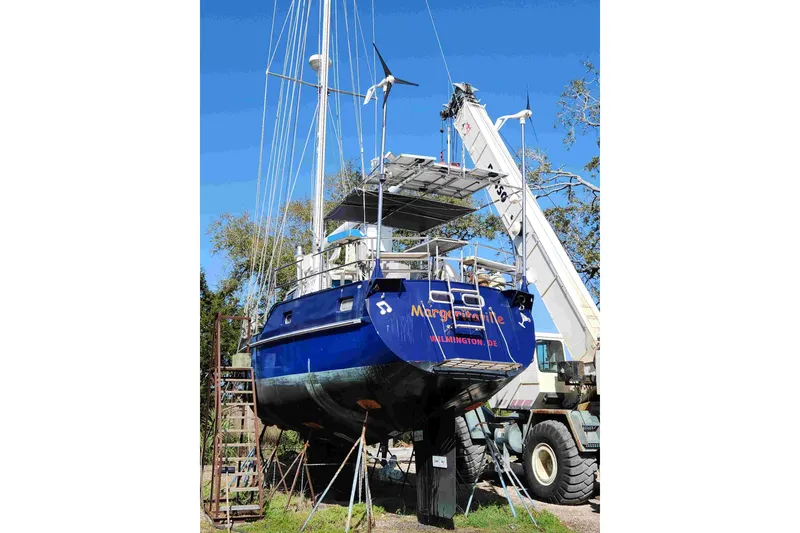 Slide: The Image of Blue Bruce Roberts sailboat from 2000 on land, supported by a crane. - 14