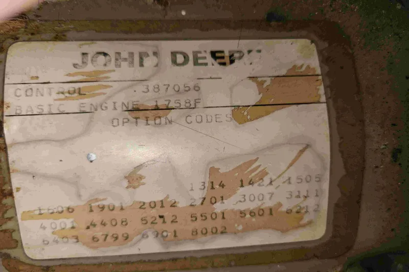 Slide: The Image of Worn John Deere label with control and engine details, showing signs of aging. - 24