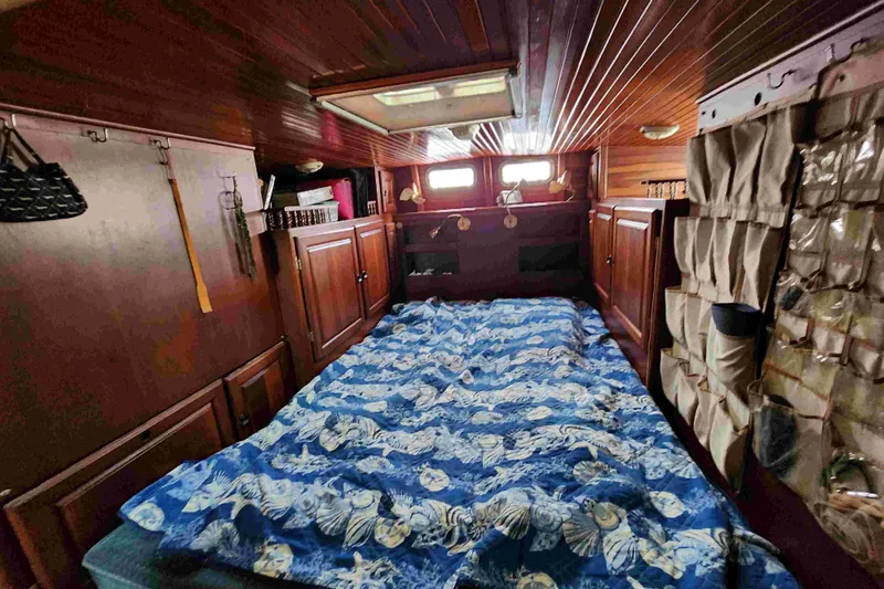 Slide: The Image of Cozy cabin interior of 2000 Custom Bruce Roberts boat with wooden paneling and blue bedding. - 9