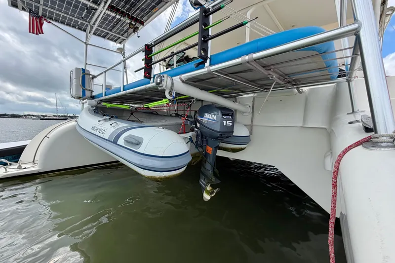 Slide: The Image of Catamaran Dolphin 460 with dinghy and Yamaha motor, featuring solar panels and American flag. - 23
