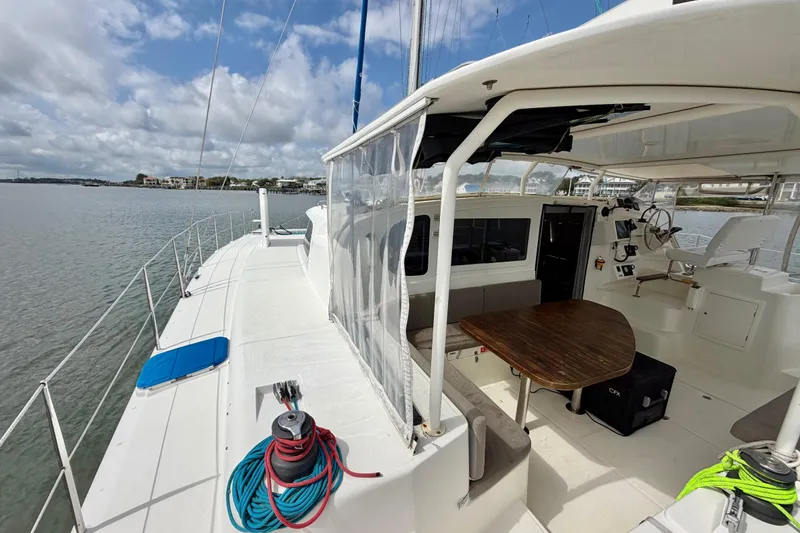 Slide: The Image of 2007 Dolphin 460 catamaran with spacious deck and seating area, docked by calm waters. - 28