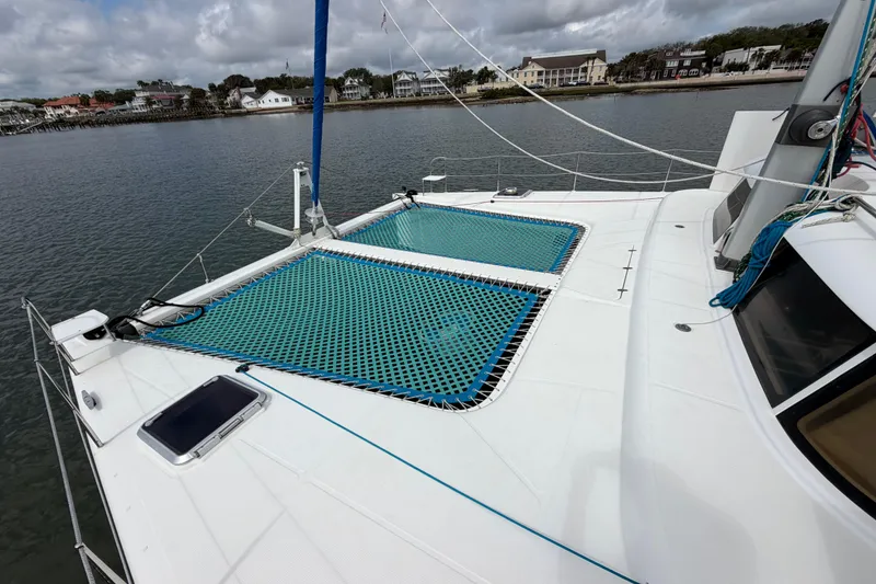 Slide: The Image of Sailing catamaran Dolphin 460, 2007 model, with blue netting on deck, docked by waterfront homes. - 31