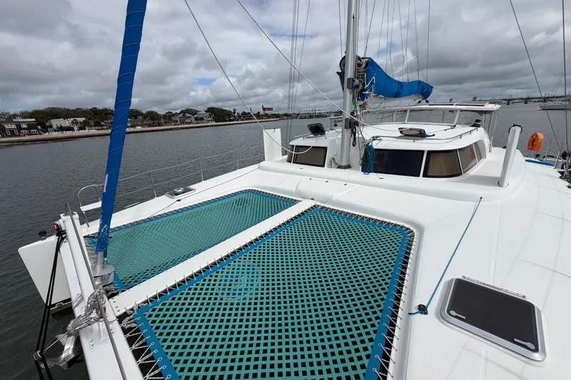 Slide: The Image of 2007 Dolphin 460 catamaran with blue netting, docked by a scenic waterfront. - 32