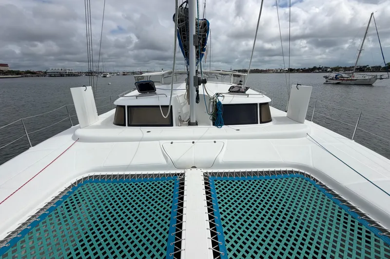 Slide: The Image of 2007 Dolphin 460 catamaran on calm water, featuring spacious deck and netting. - 33