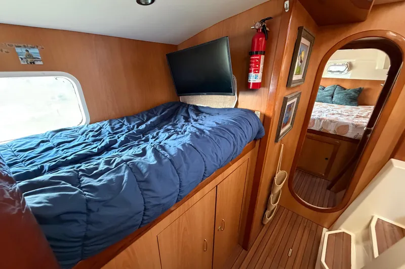Slide: The Image of Cozy cabin interior of 2007 Dolphin 460 yacht with blue bedding and wooden accents. - 63