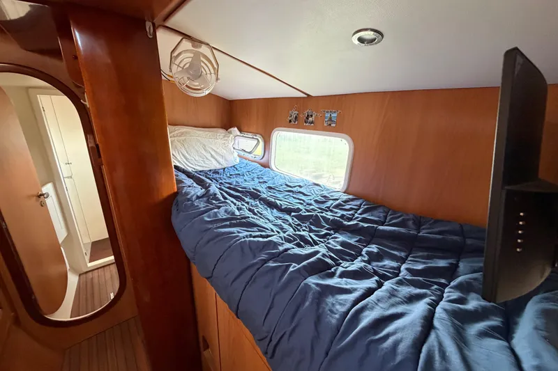 Slide: The Image of Cozy cabin interior of 2007 Dolphin 460 yacht with blue bedding and wooden finish. - 64
