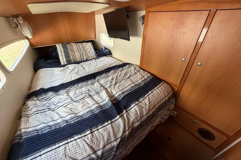 Slide: The Image of Cozy bedroom in 2007 Dolphin 460 yacht with striped bedding and wooden cabinetry. - 85