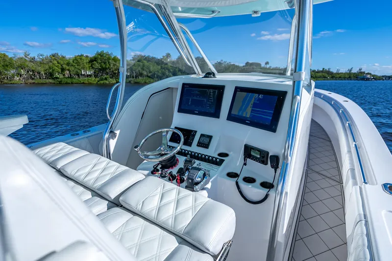 Slide: The Image of 2019 Contender 39 Fisharound boat cockpit with modern navigation displays on a sunny day. - 17