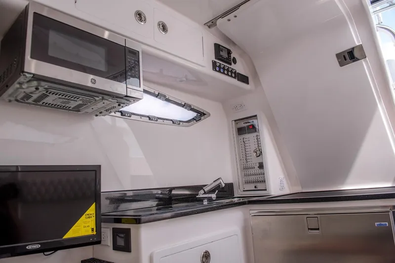 Slide: The Image of Manufacturer Provided Image: 2019 Contender 39 Fisharound interior kitchen with microwave, TV, and control panel. - 33