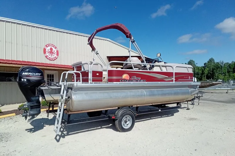 Slide: The Image of 2014 Sun Tracker Party Barge 20 DLX pontoon boat on trailer, parked outside a building. - 10