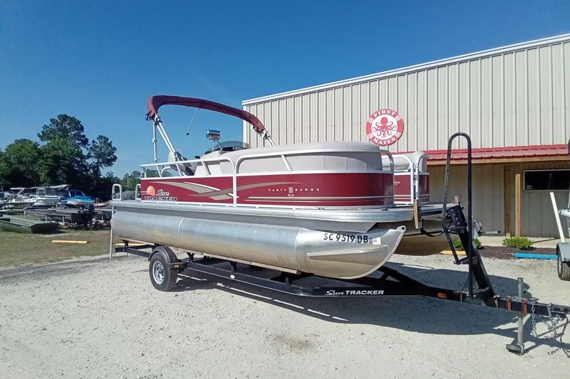 Slide: The Image of 2014 Sun Tracker Party Barge 20 DLX pontoon boat on trailer, parked outside a building. - 3