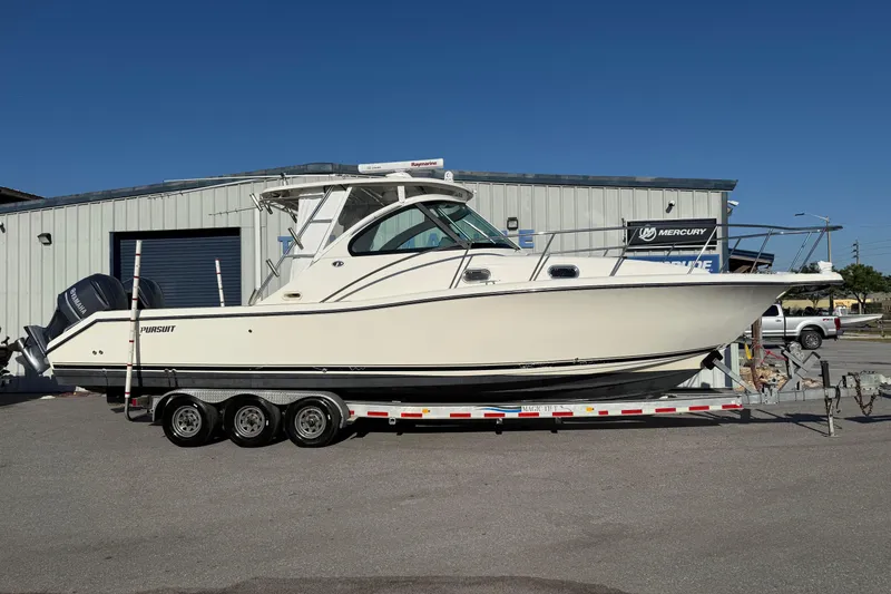 The Image of 2007 Pursuit OS 335 Offshore boat on trailer, parked outside a metal building. - 1