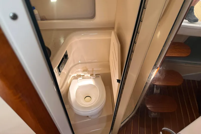Slide: The Image of 2007 Pursuit OS 335 Offshore boat bathroom with compact toilet and wooden steps. - 16