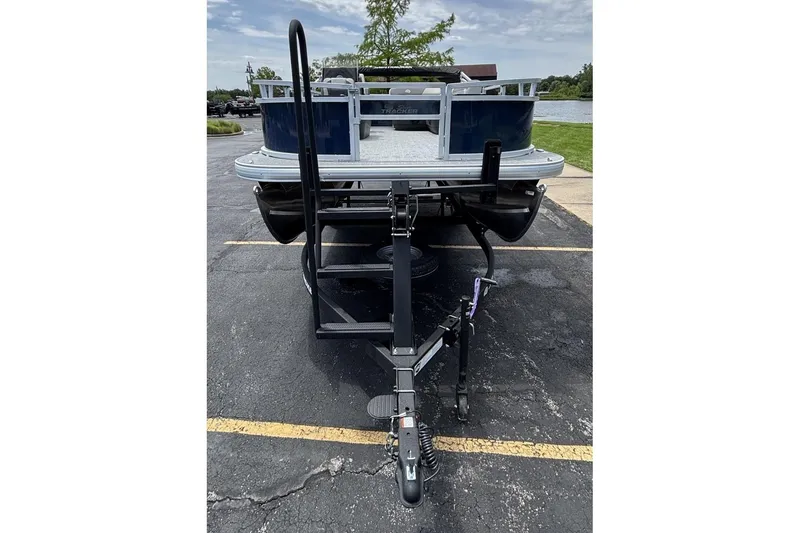 Slide: The Image of 2026 Sun Tracker Bass Buggy 16 XL Select pontoon boat on trailer, parked outdoors. - 2